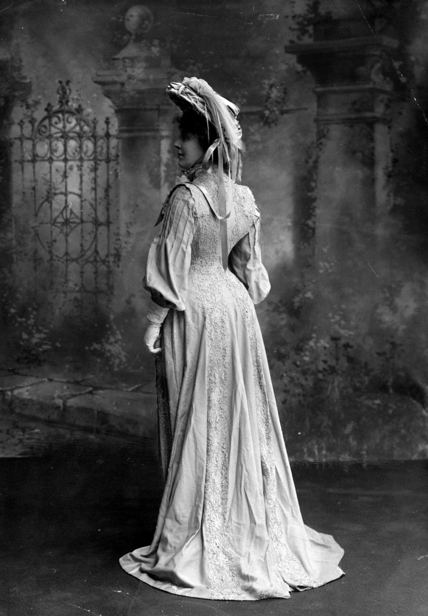 #45 Miss Mansfield wears a coatdress with lace detail and full sleeves, complete with a feather-trimmed hat