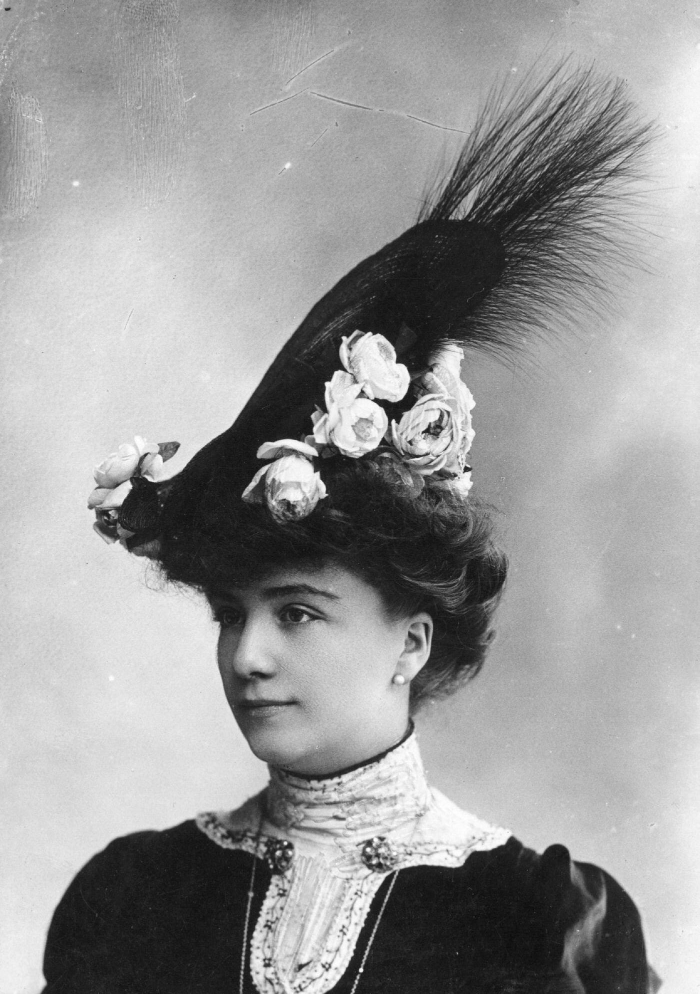 #57 An Edwardian woman wears a high hat decorated with flowers and feathers in 1903