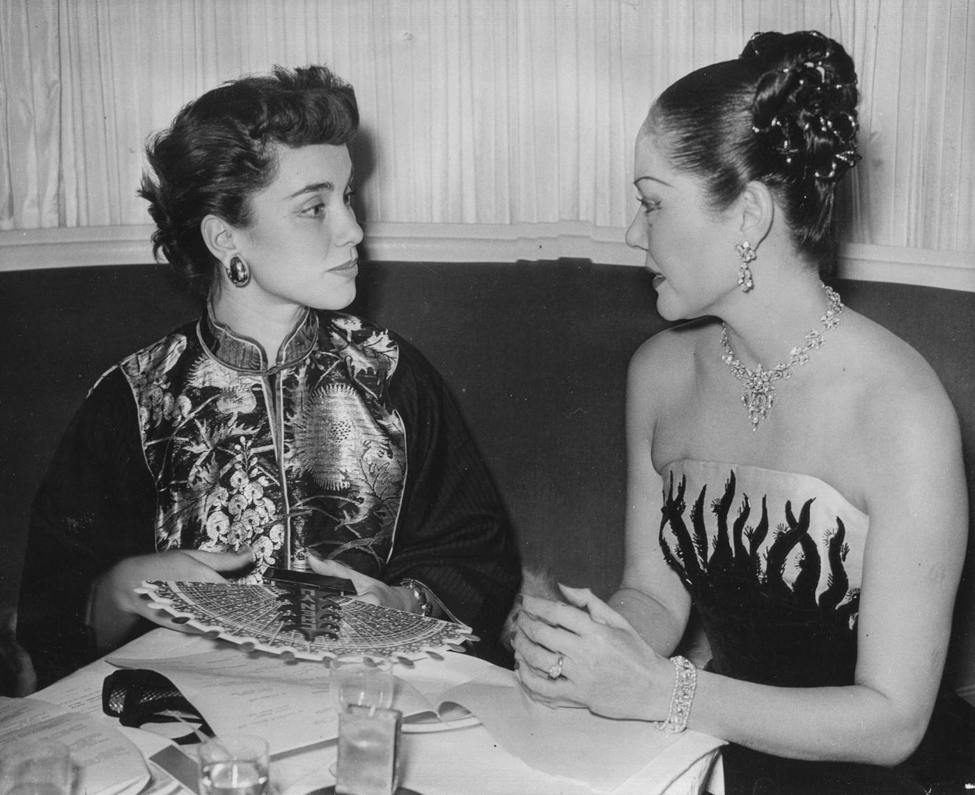 #17 Actress Linda Christian (left) wearing a traditional Chinese jacket and talking to Chinese-born compere Seignon at a Christmas Party held by Chen Yu nail lacquers at the Embassy Club in London, October 28th 1950.