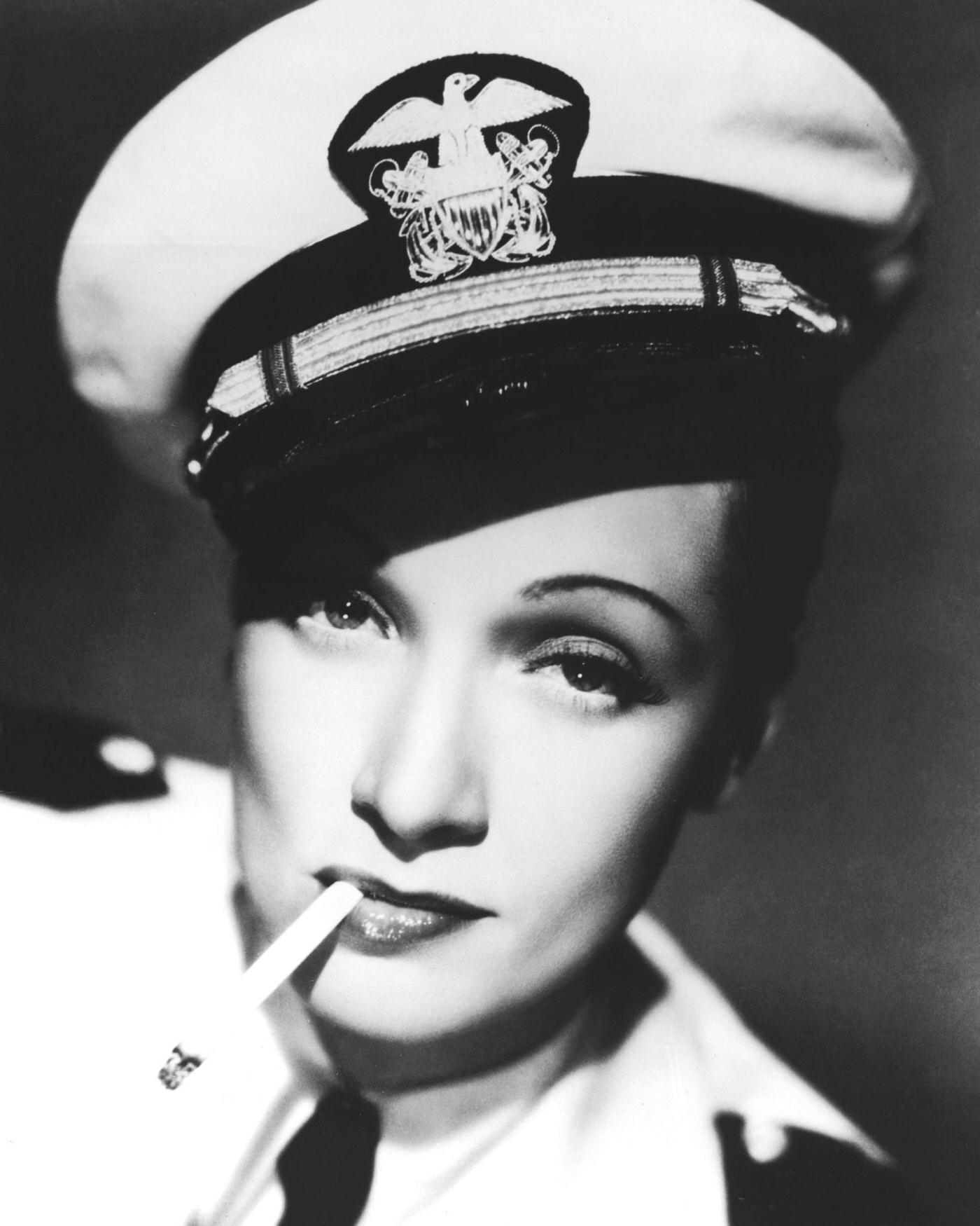 #24 Marlene Dietrich looks stylish in a sailor’s cap and cigarette in a promotional portrait for ‘Seven Sinners.’