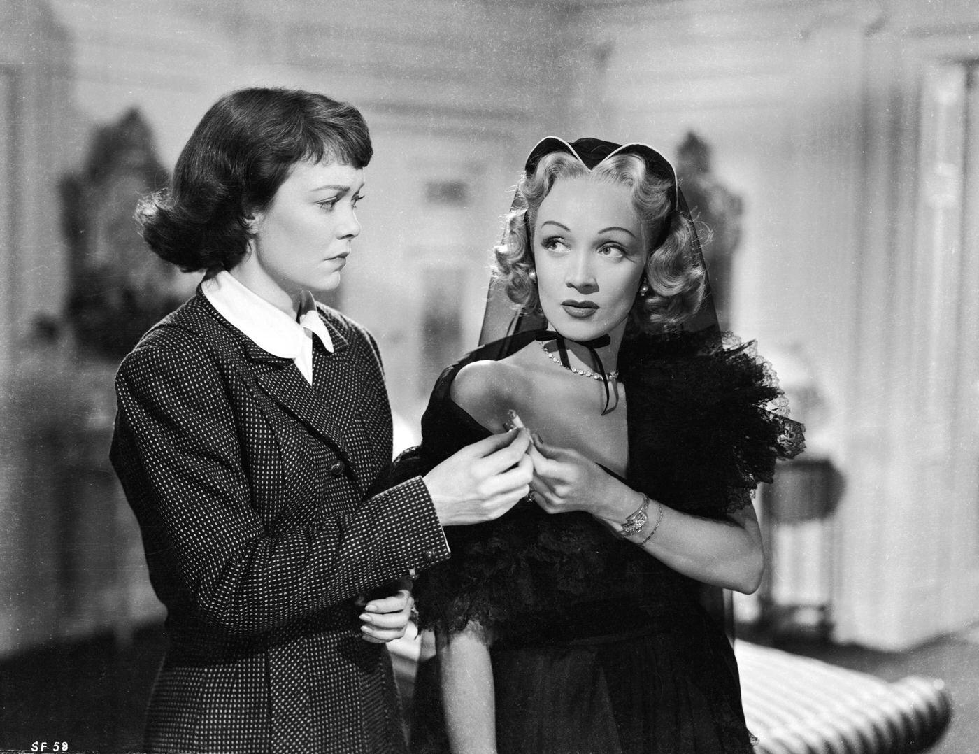 Jane Wyman and Marlene Dietrich share a cigarette in a scene from the 1950 murder mystery ‘Stage Fright.’