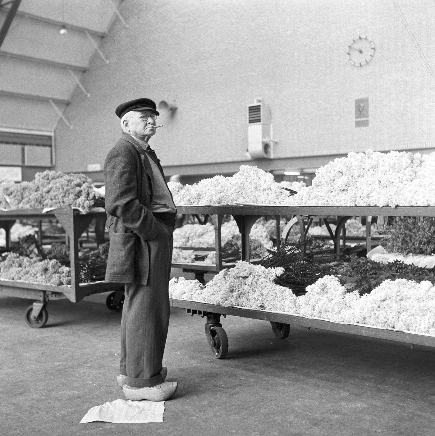 #30 A man wearing traditional Dutch clogs with flower carts in the background, Amsterdam, the Netherlands, 1954.