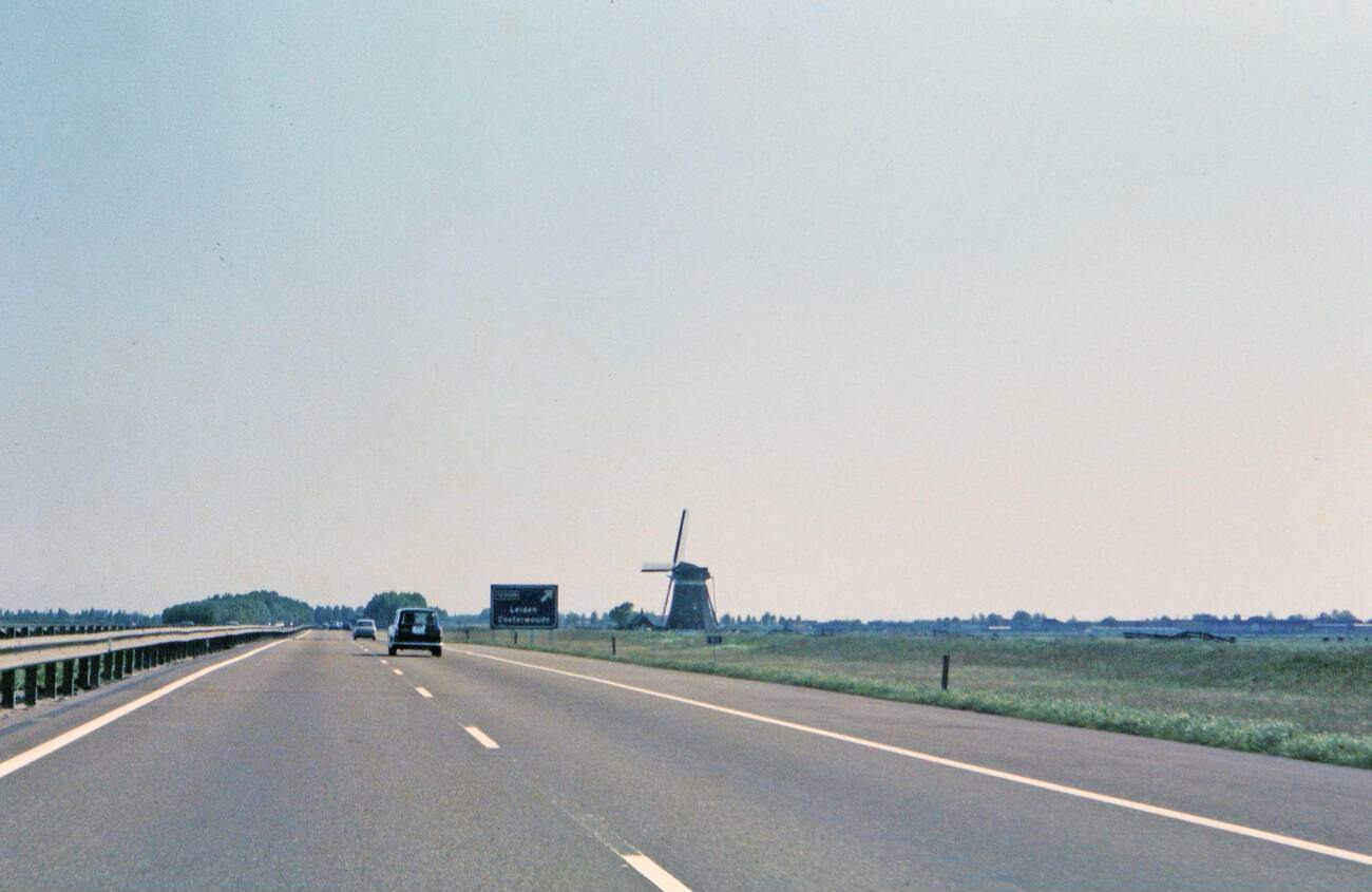 #22 A car driving on a highway near Leiden, The Netherlands, with a windmill visible on the side of the highway, in 1972.