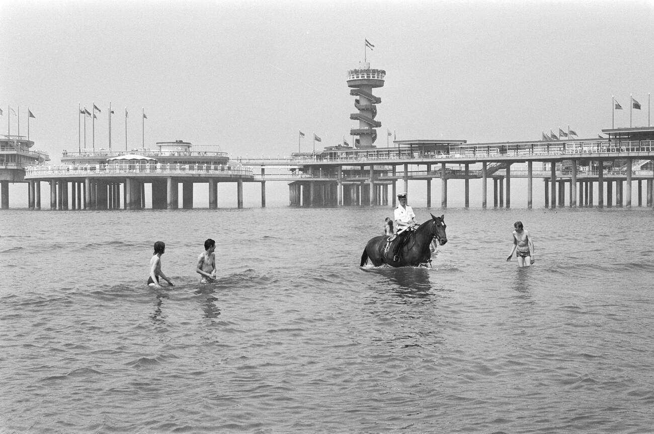 #10 Police on horseback in the water retrieving people who are too far out to sea at Scheveningen beach in 1976.