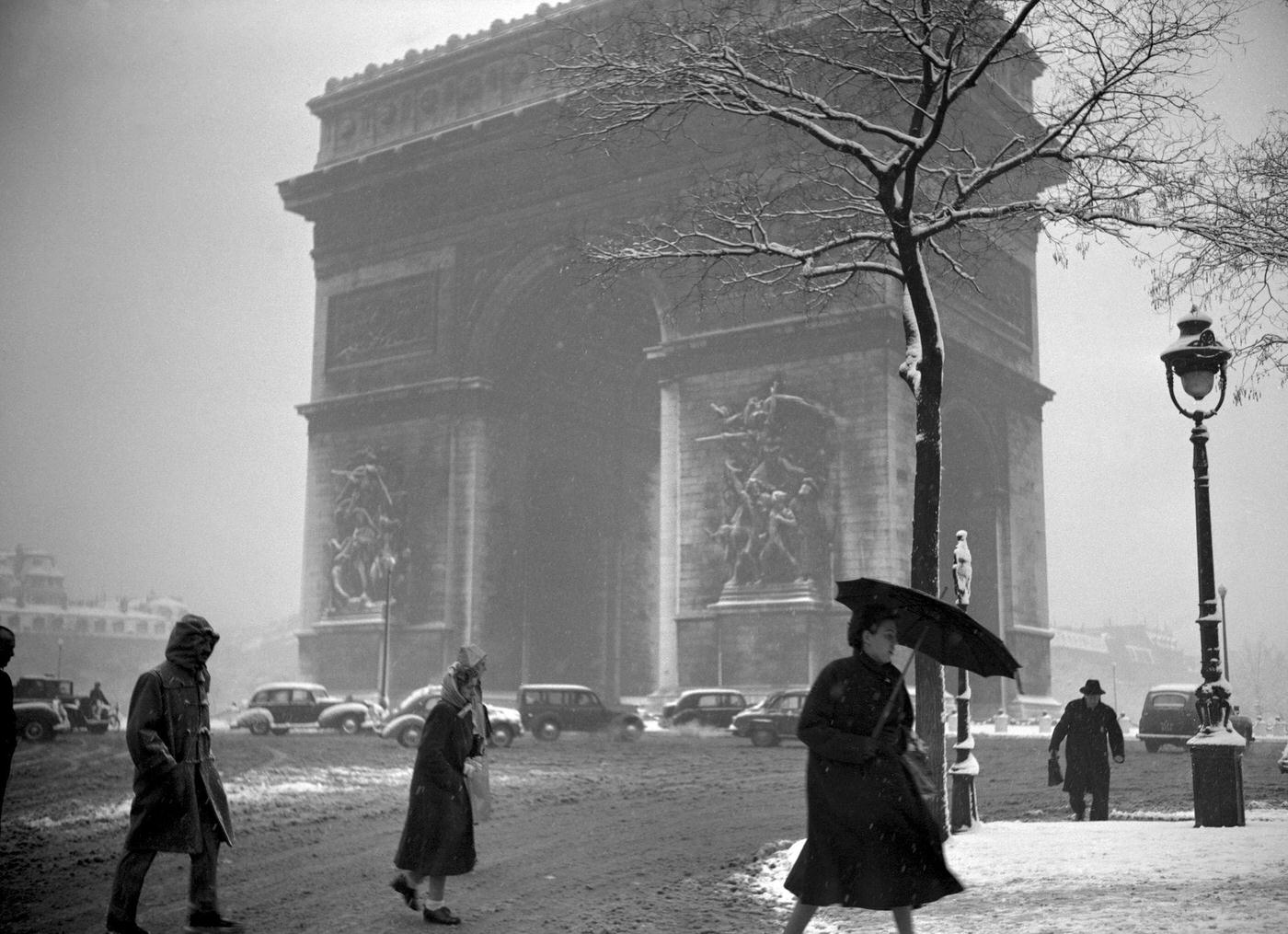 #60 People Walking In The Muddy Snow Near The Arc de Triomphe, Paris, During The 1952 Winter.