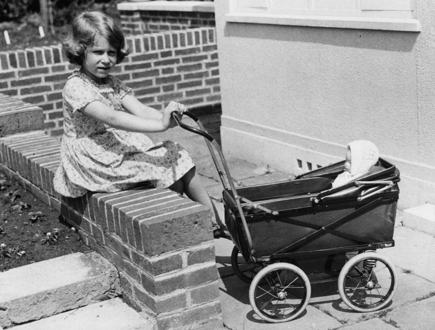 #50 A childhood photograph from 1933 shows Queen Elizabeth II with a toy doll in a pram, in the grounds of the Royal Lodge at Windsor.