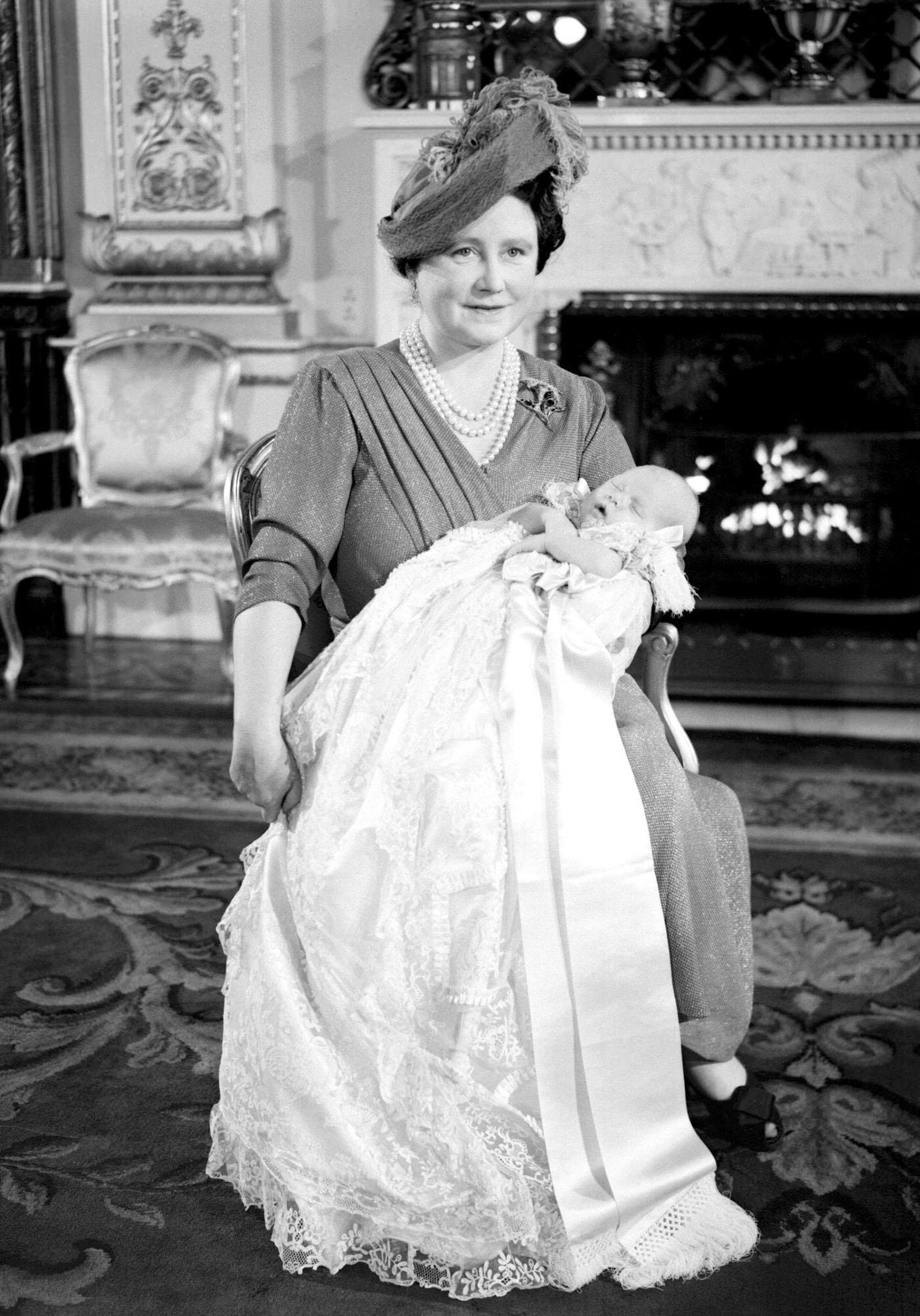 #116 Queen Mother holding her first grandchild Prince Charles at his christening at Buckingham Palace, 1950.