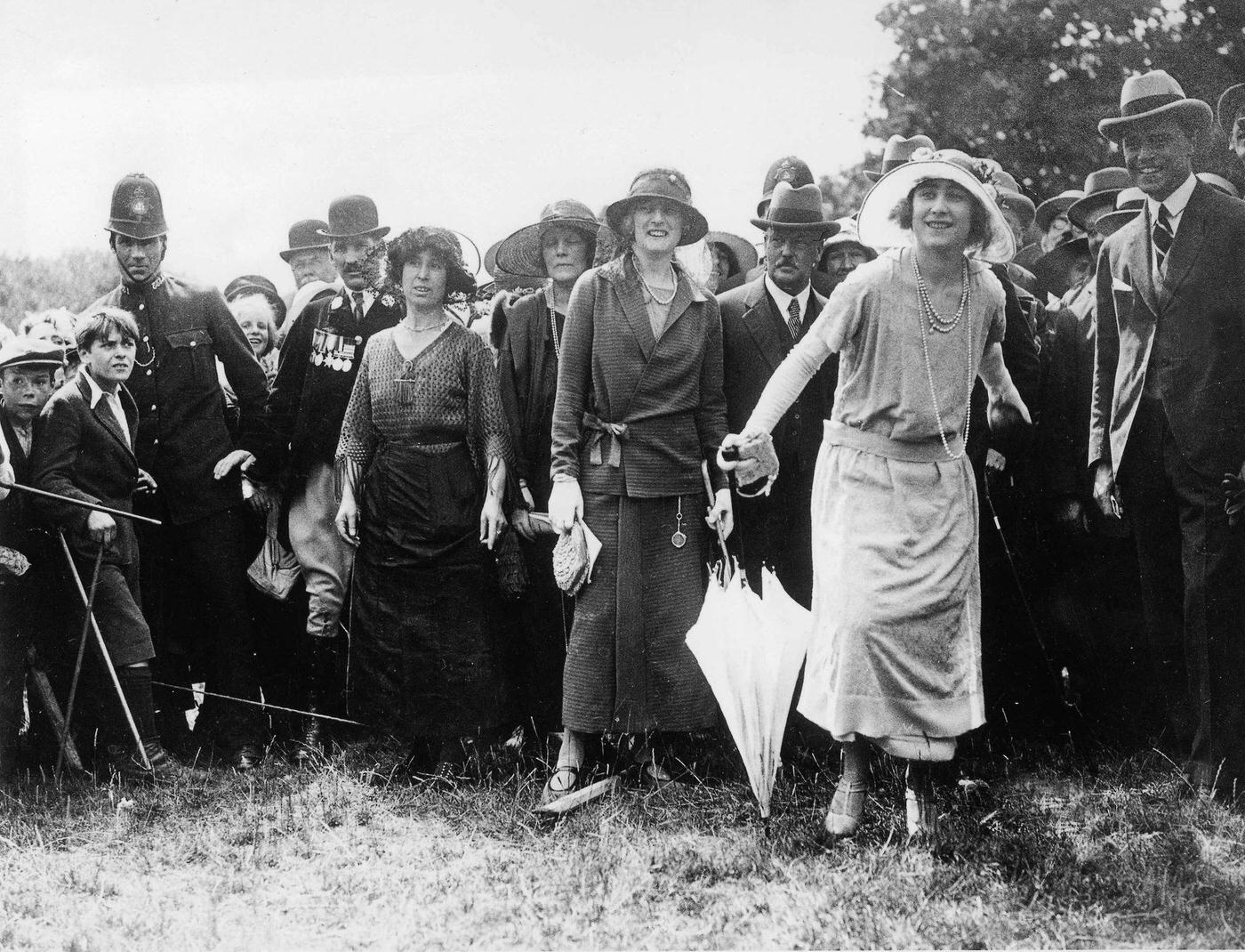 #34 Queen Elizabeth trying her luck at the coconut shy during a visit to Loughton, Essex as Duchess of York