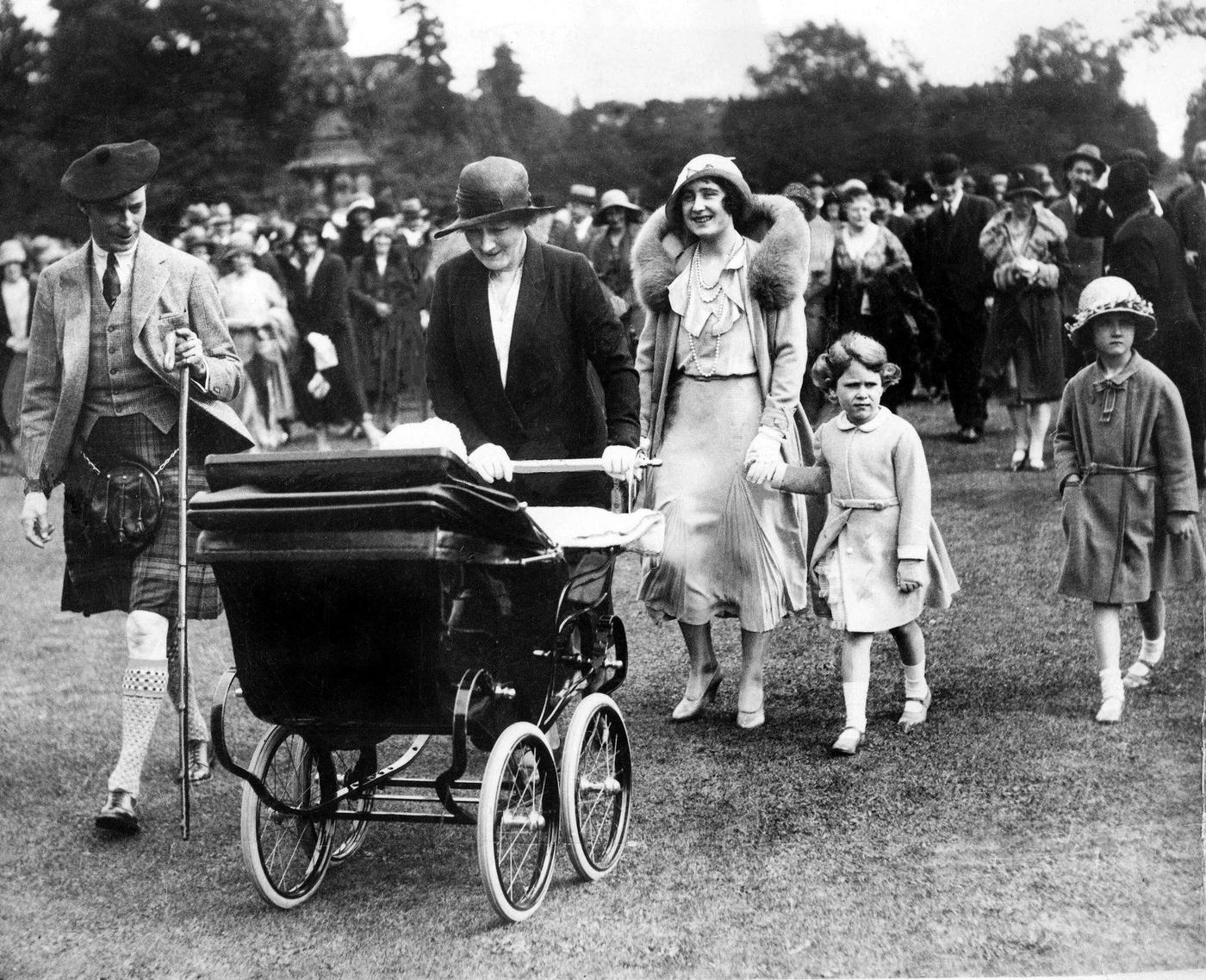 #75 King George VI and Queen Elizabeth with Princesses Elizabeth and Margaret in a pram at a garden party, 1931.