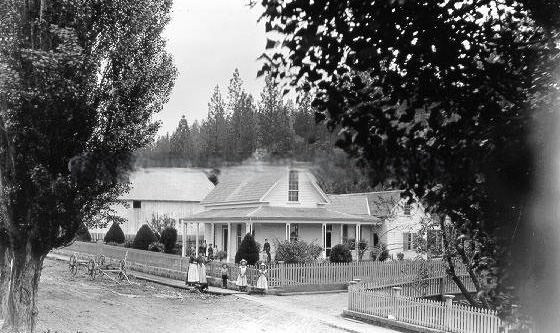 #165 Large family group stands in front of house and fence, 1895