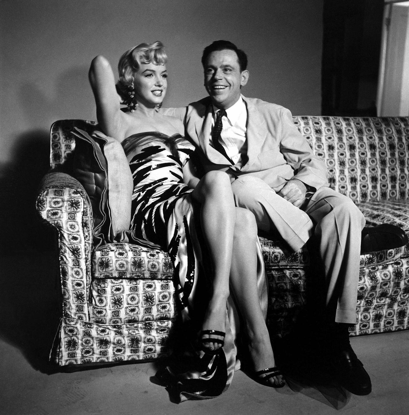 Marilyn Monroe wearing a tiger-striped dress sits next to co-star Tom Ewell in 1954 during the filming of “The Seven Year Itch”