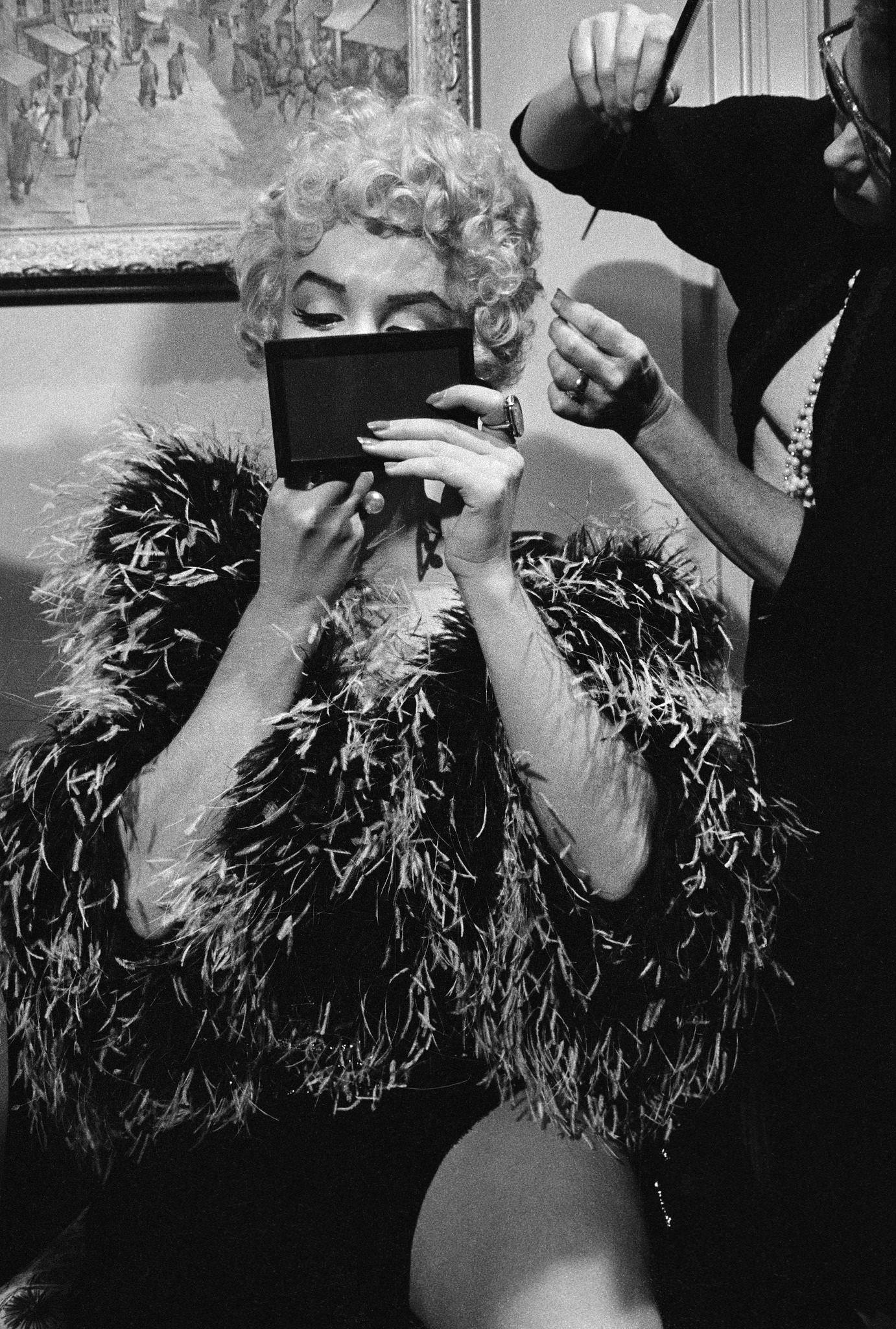 Marilyn Monroe wearing a feather boa puts on makeup to prepare for a scene during the filming of “The Seven Year Itch” in 1954