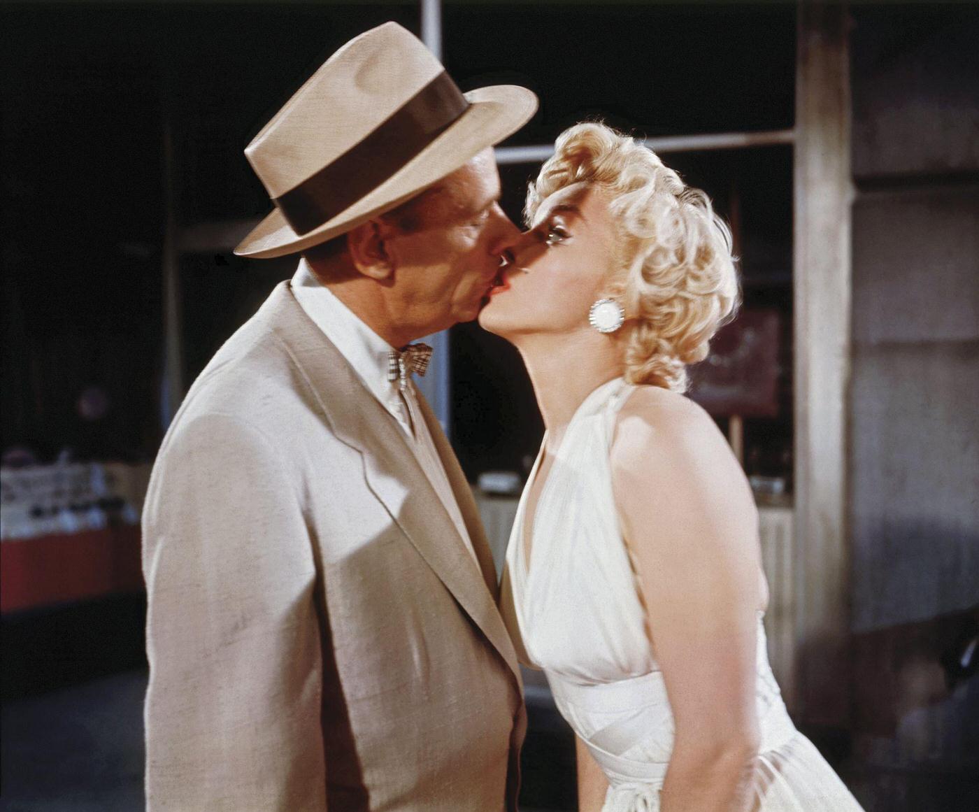 Marilyn Monroe kisses co-star Tom Ewell while wearing a white dress during the making of the famous skirt-blowing scene on set in 1954 during the filming of “The Seven Year Itch”