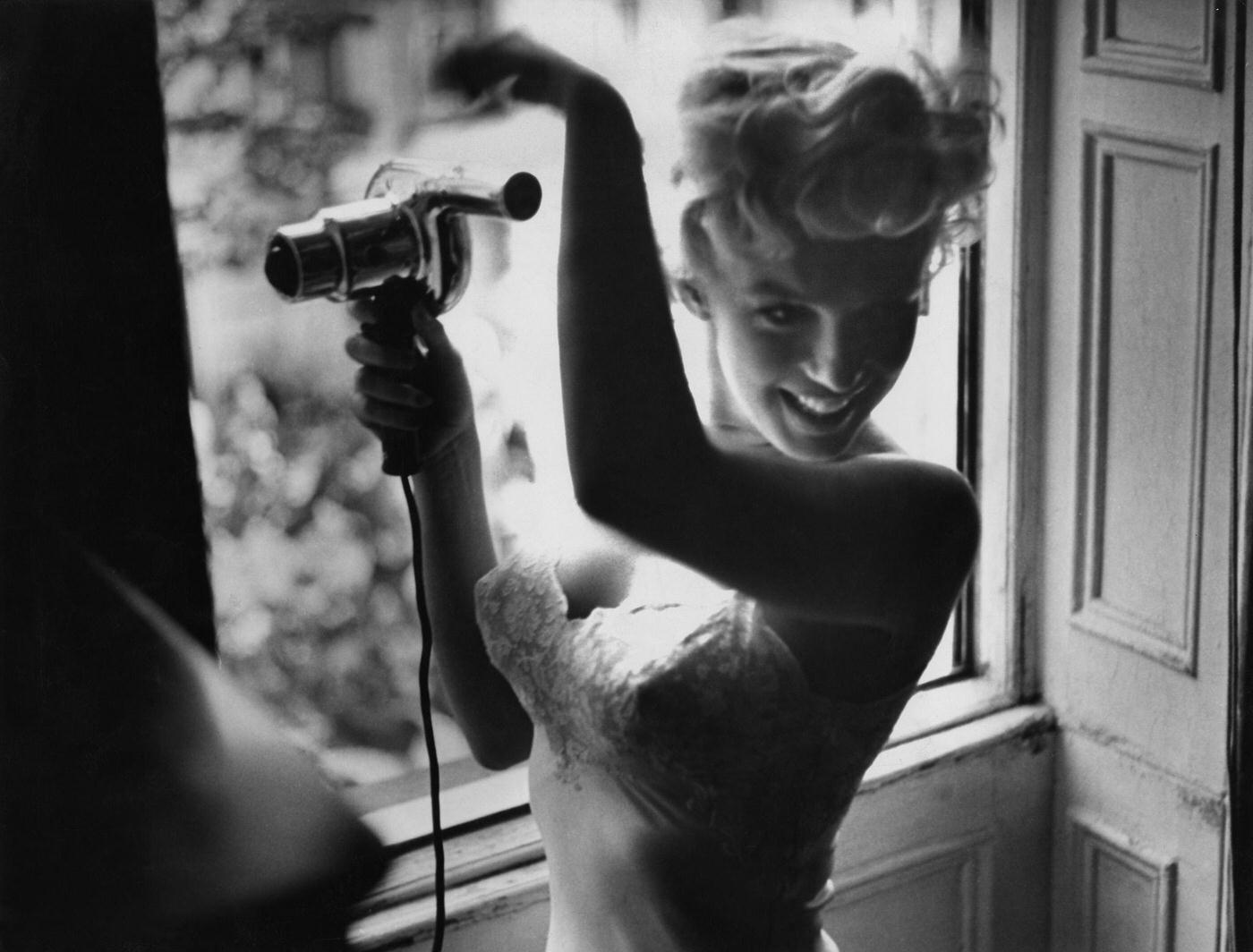 Marilyn Monroe blow-dries her hair in front of an open window in 1954 during the filming of “The Seven Year Itch” in New York