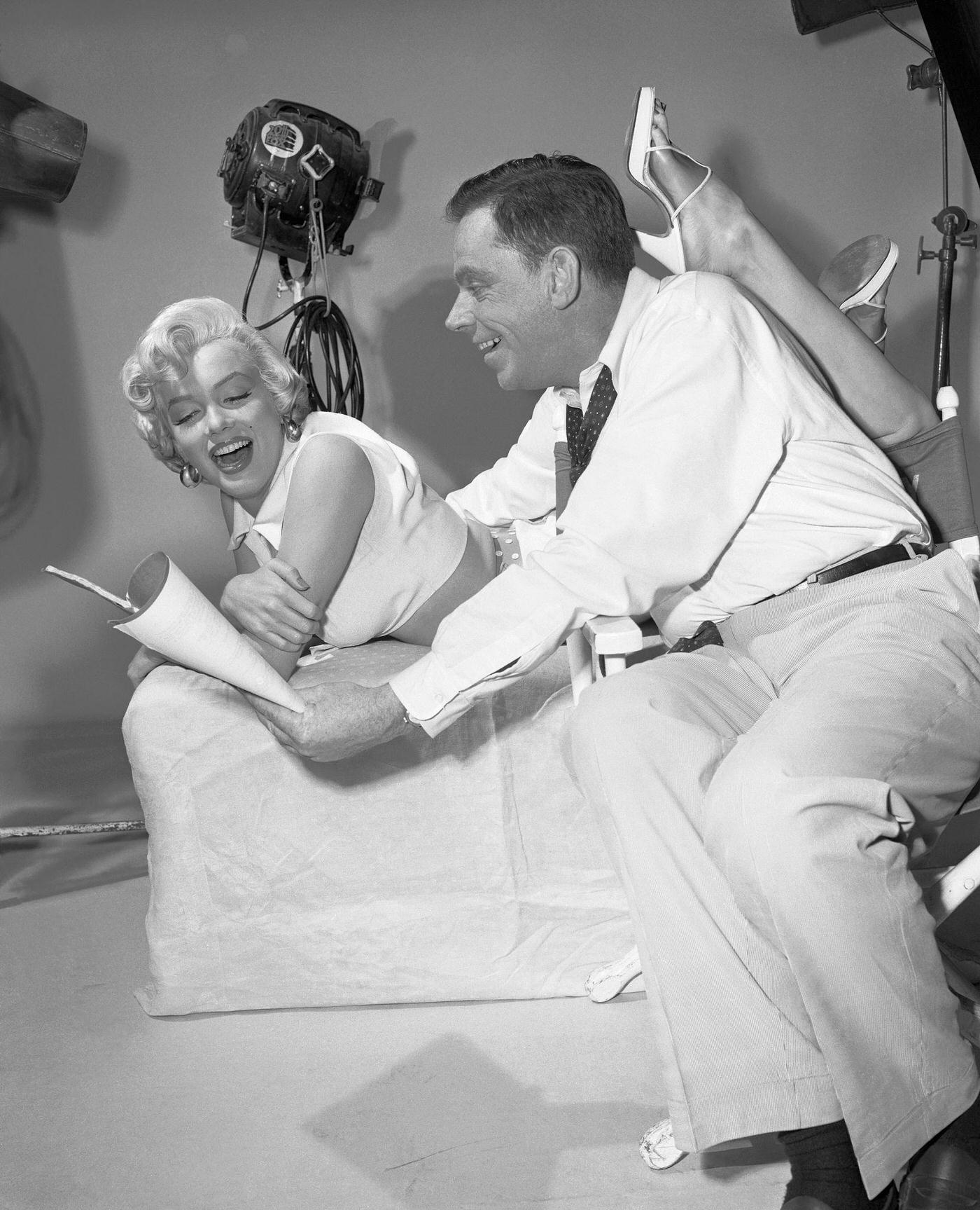 A crowd stands in front of Loew’s State movie theater in Times Square with a cut-out of Marilyn Monroe with the skirt of her white dress blowing from the famous scene in “The Seven Year Itch” in 1955.
