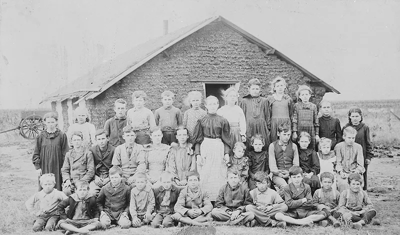 #106 This photograph from 1895 shows a teacher and her students posing in front of a sod schoolhouse in Woods County, Oklahoma.