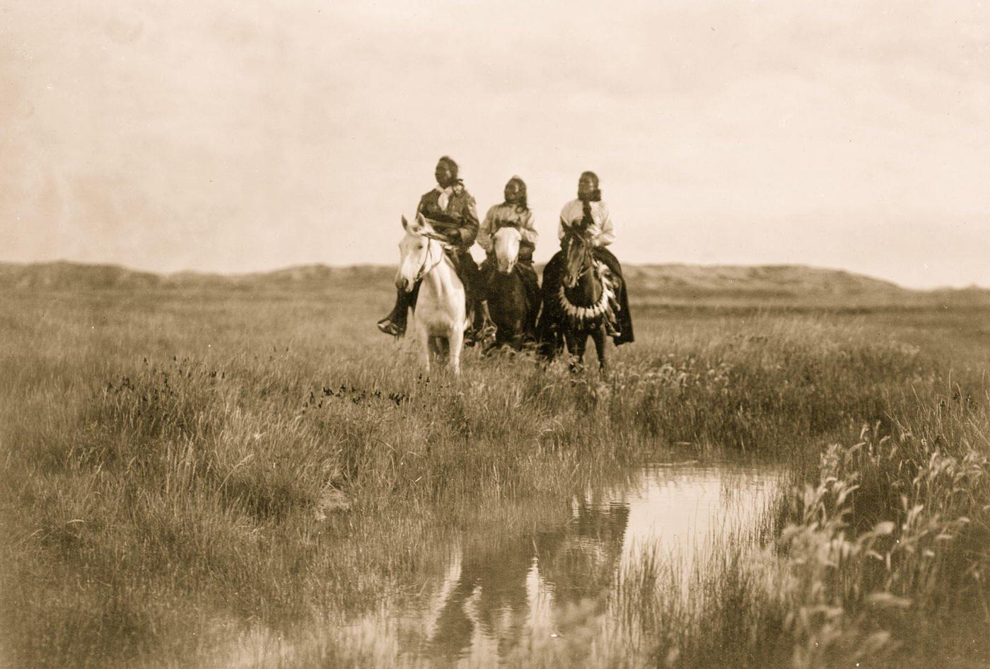 #17 Three Sioux Indians on horseback facing front by pond on plains, 1905
