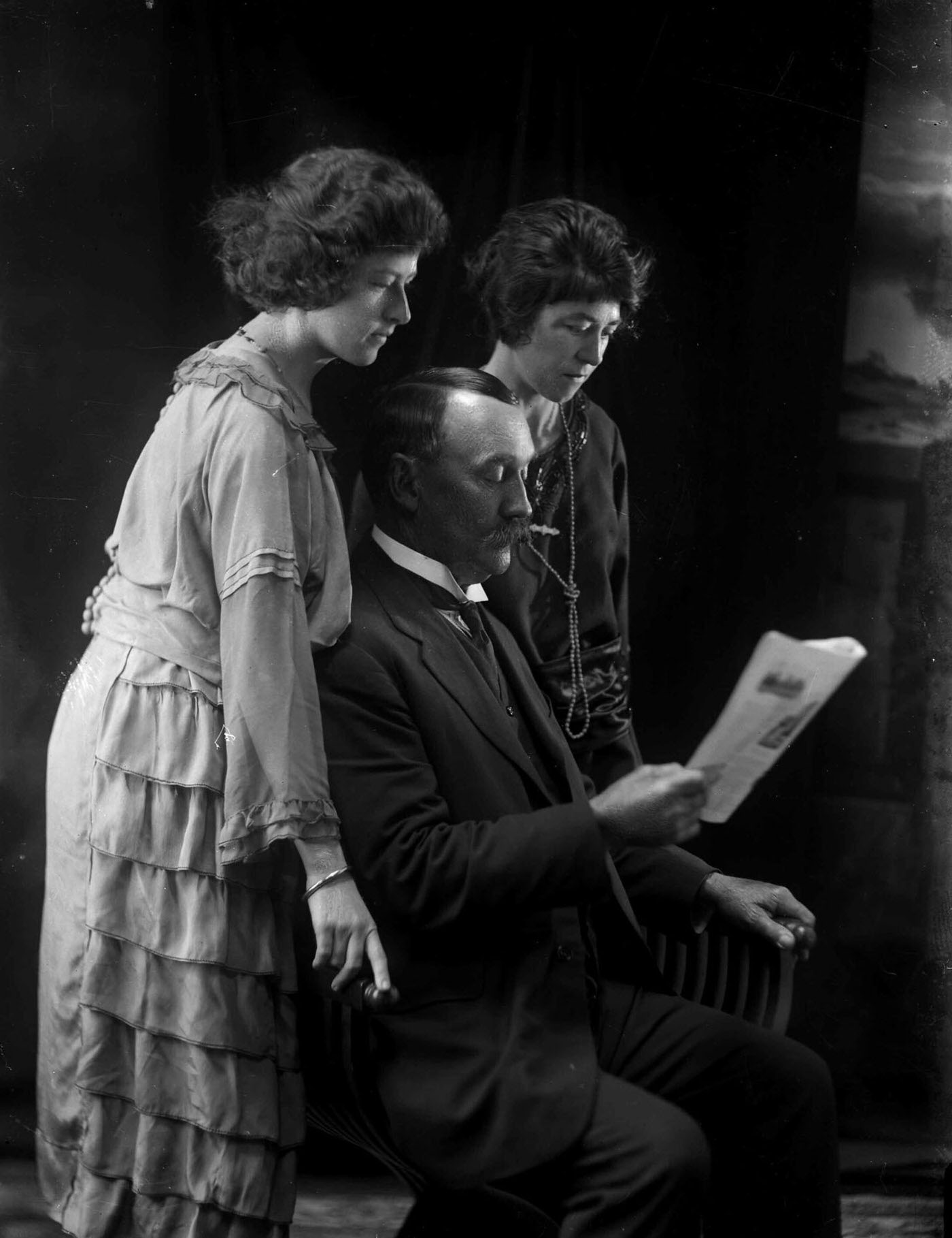 #16 Group portrait featuring two ladies and a man reading a paper