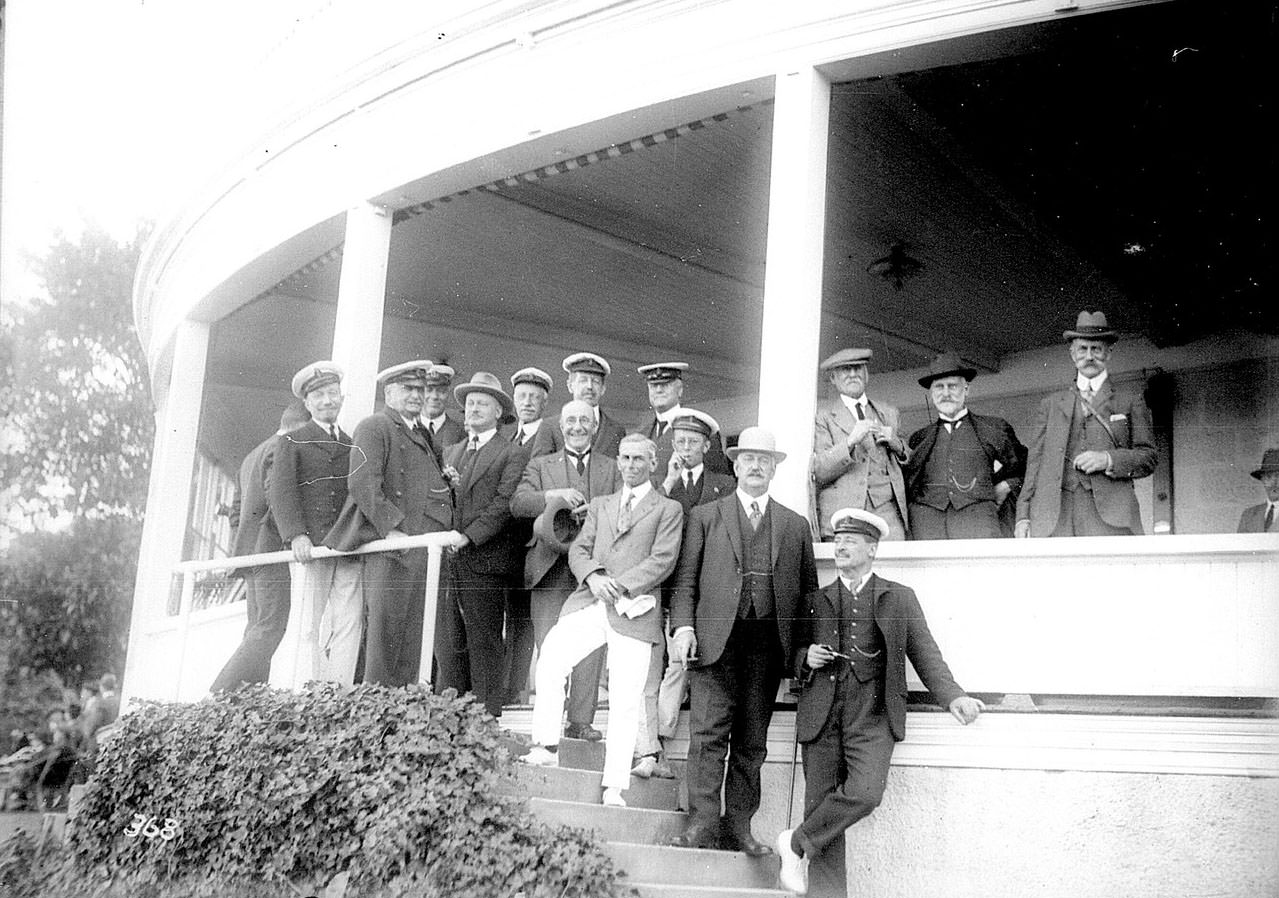 #46 Men in yachting uniforms standing on the verandah of an unidentified yacht club