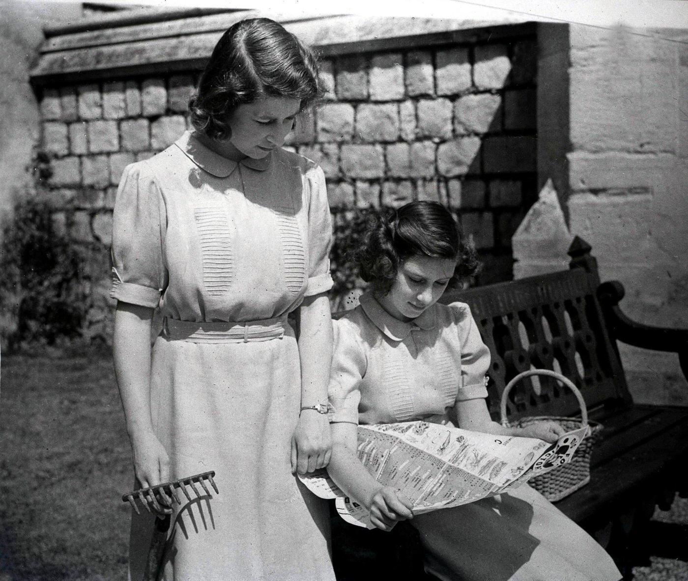 #24 Princesses Elizabeth and Margaret study the Ministry of Agriculture’s cropping chart in their allotments on the east side of Windsor Castle during World War Two, England, 1940’s.