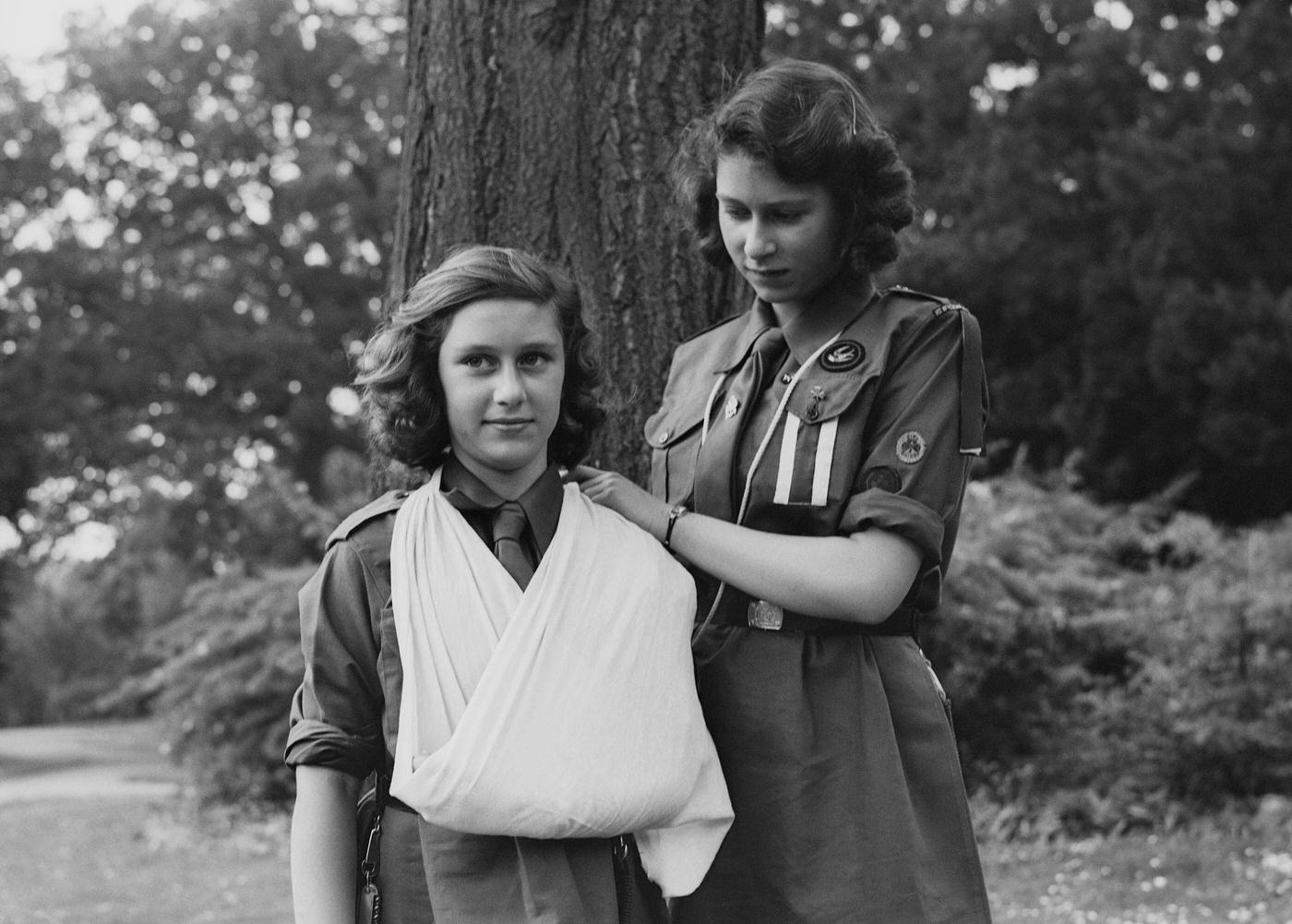 #61 Princess Elizabeth places Princess Margaret’s arm in a sling as part of the girl guides in Frogmore, Windsor, England on April 11, 1942.
