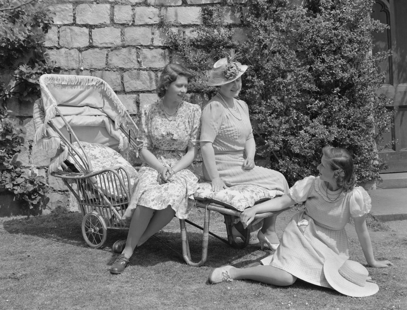 #71 Princess Elizabeth and Queen Elizabeth, The Queen Mother, seated on a sun lounger with Princess Margaret seated on the grass in the garden at Windsor Castle, 1944