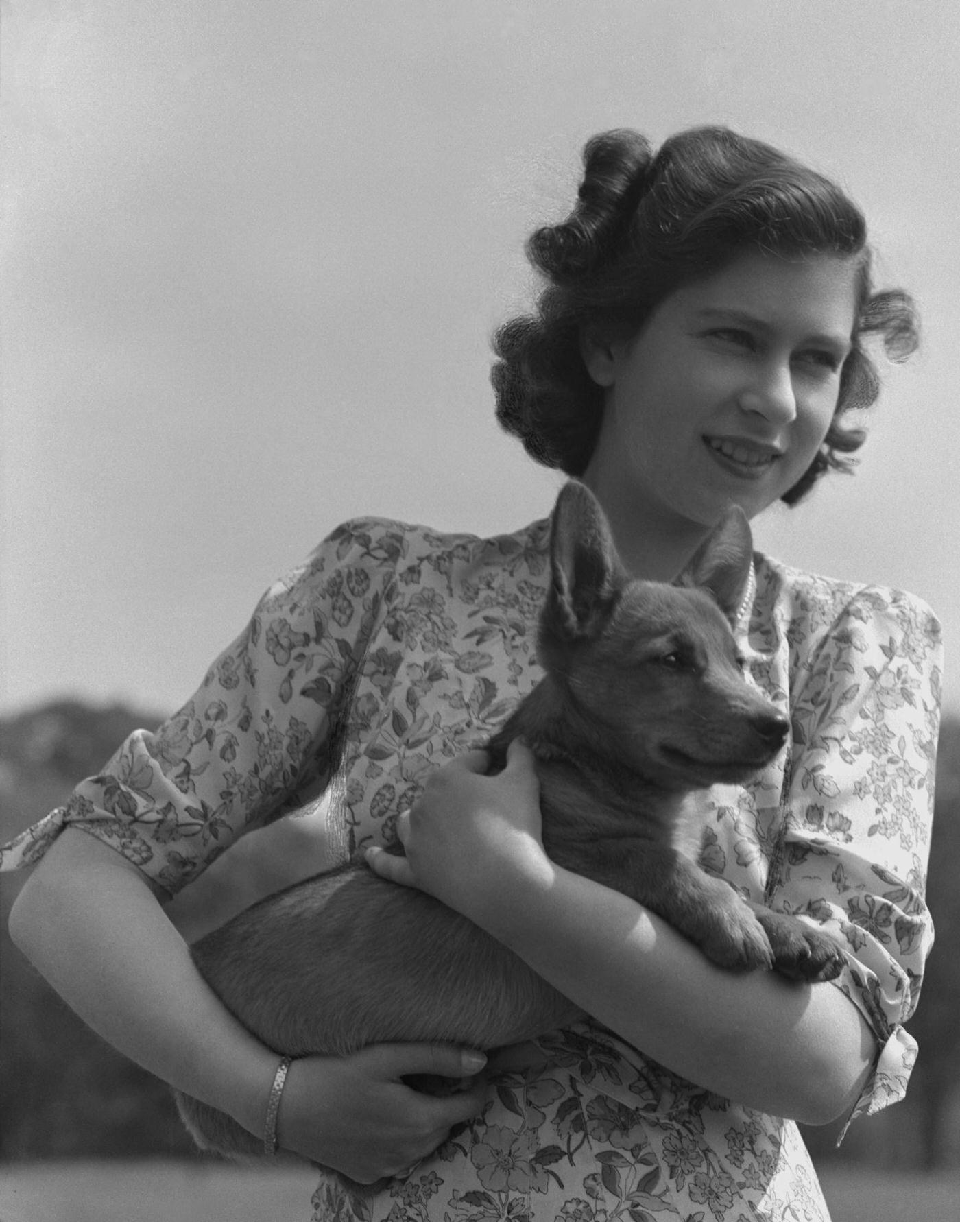 #72 Princess Elizabeth pictured holding a corgi in the grounds of Windsor Castle, 1944