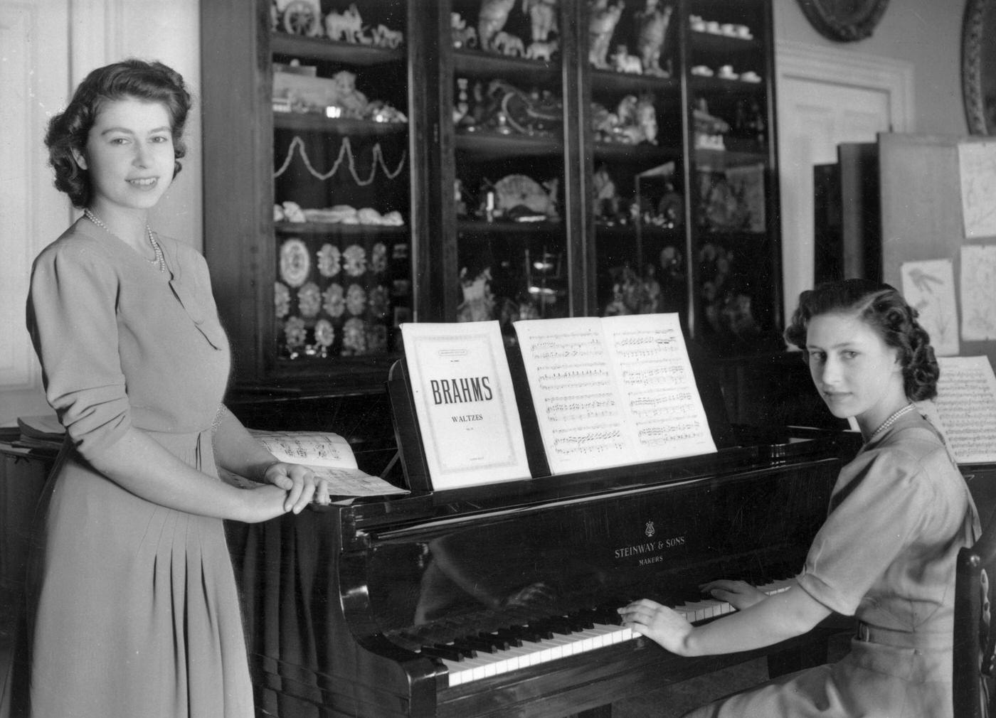 #87 Princess Elizabeth and Princess Margaret Rose at a piano in the school room of Buckingham Palace, London, 19 July 1946.