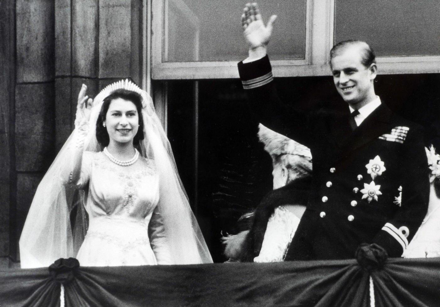 #90 Princess Elizabeth (now The Queen) and Prince Philip, The Duke of Edinburgh, wave to crowds from the balcony of Buckingham Palace following their marriage, London, England, 20 November 1947.