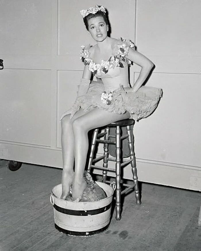 #78 Cyd Charisse resting her feet on ice, behind the cameras after rehearsals in 1948