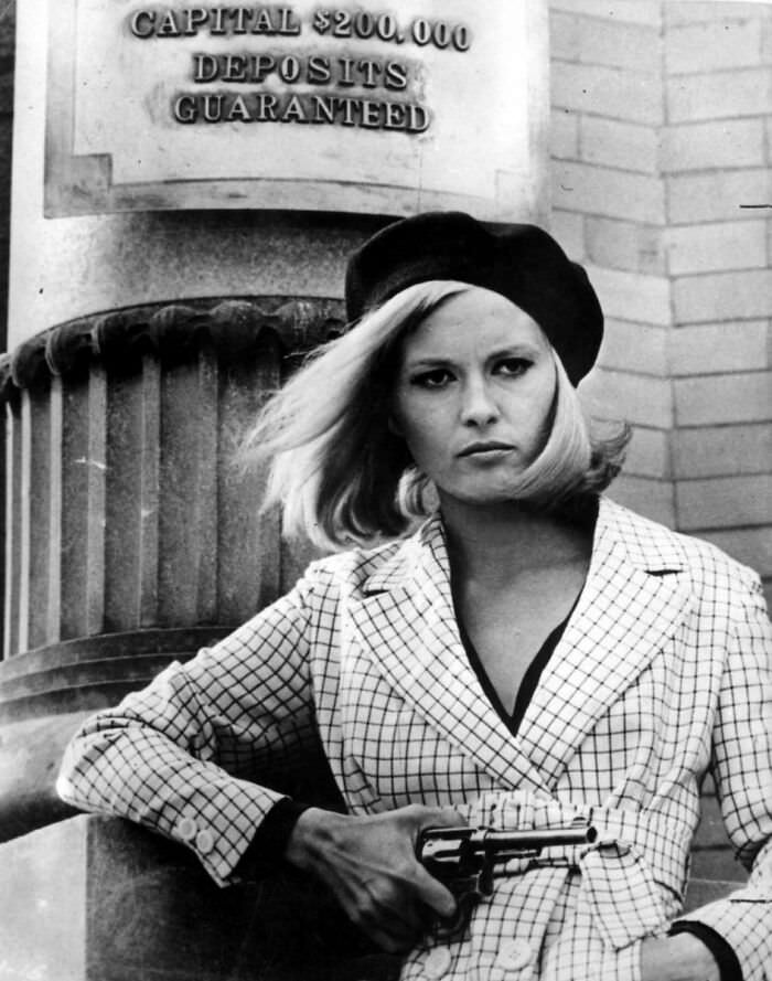 #90 Actress Faye Dunaway as Bonnie Parker, standing outside the Merchants Bank in the film ‘Bonnie and Clyde’, 1967