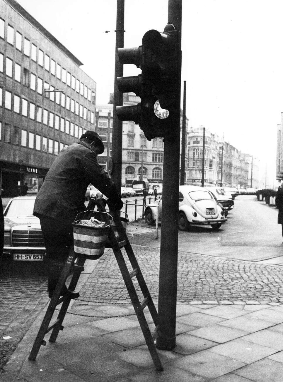 #6 A man cleaning a traffic light in the Kaiser-Wilhelm-Strasse in Hamburg, Germany in 1970.