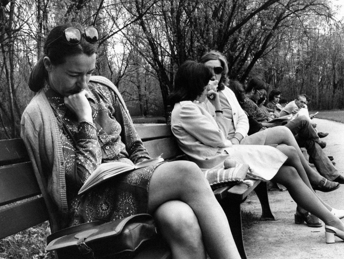 #60 German woman reading a book on a bench in a park in Hamburg, Germany in 1973.