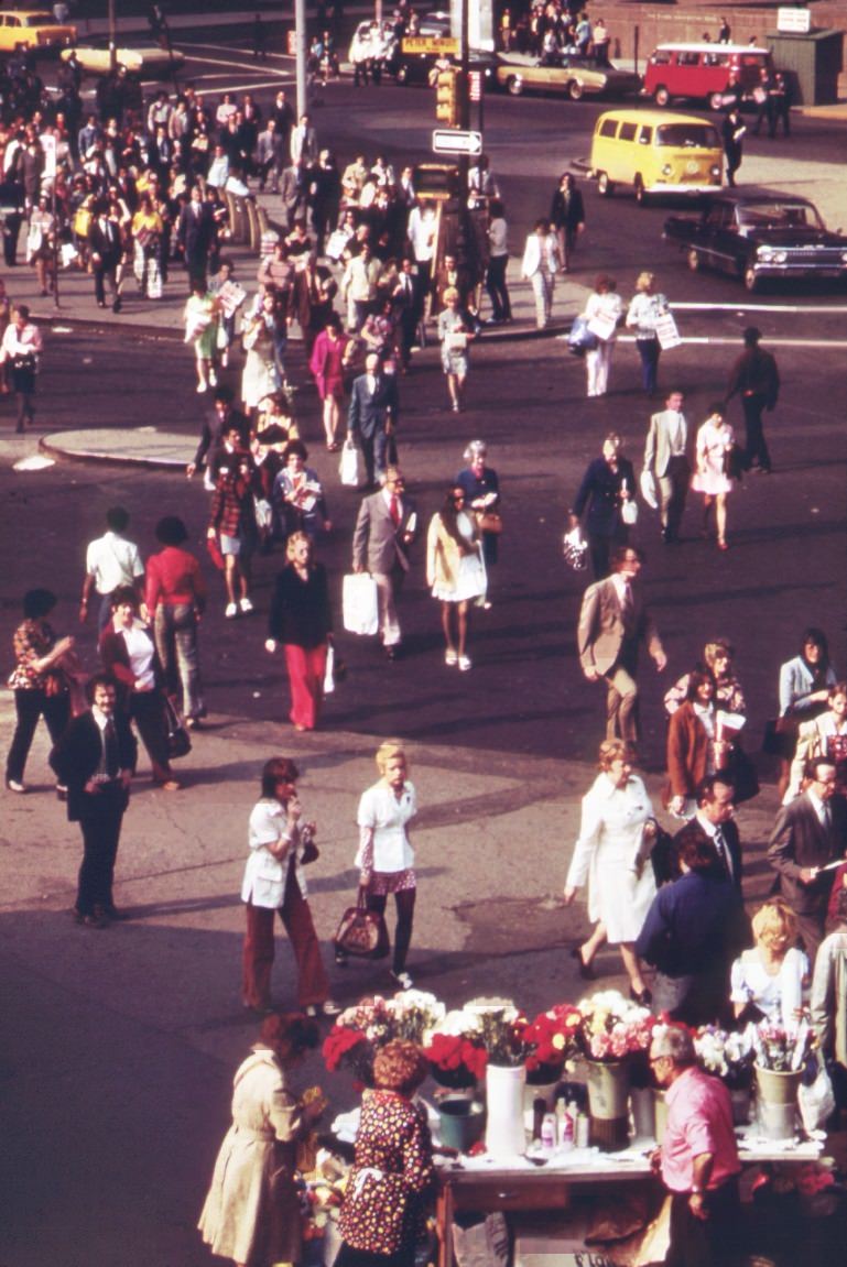 #105 Commuters head for home at rush hour near the docks of the staten island ferries in battery park, lower manhattan. Some pause at a flower-sellers’ stand, 1970s