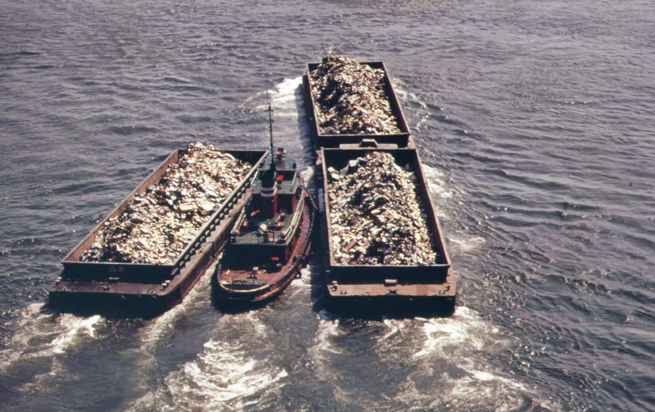 #118 Part of the 26,000 tons of solid waste that new york city produces each day. Tugs tow heavily-laden barges down the east river to the overflowing staten island landfill, 1970s