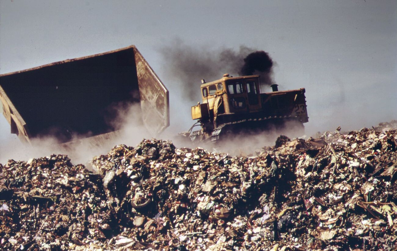 #2 In last stage of city waste disposal process, garbage brought by barge from manhattan is dumped from carts at outer edges of staten island landfill. Previously deposited refuse is already smoldering, 1970s