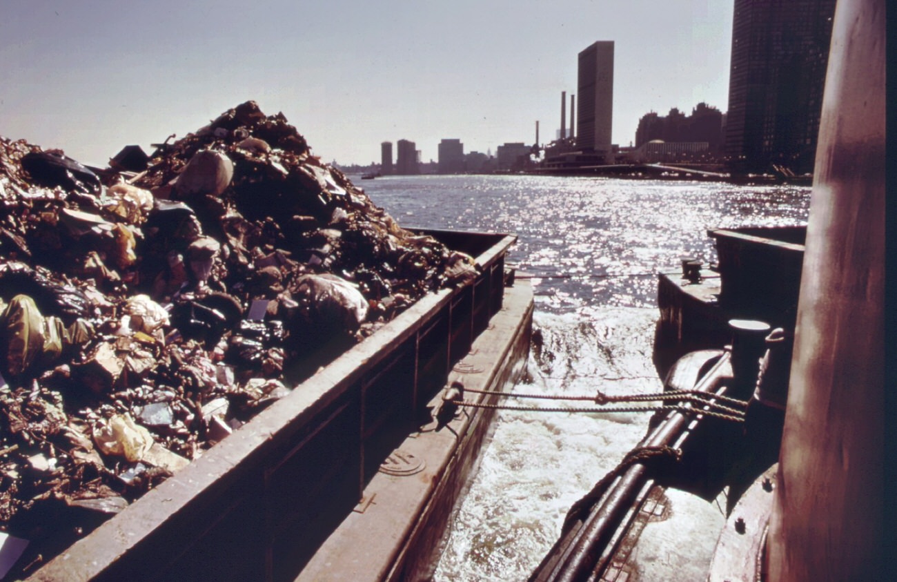 #57 Garbage is towed down the east river to staten island landfill, manhattan in background, 1970s