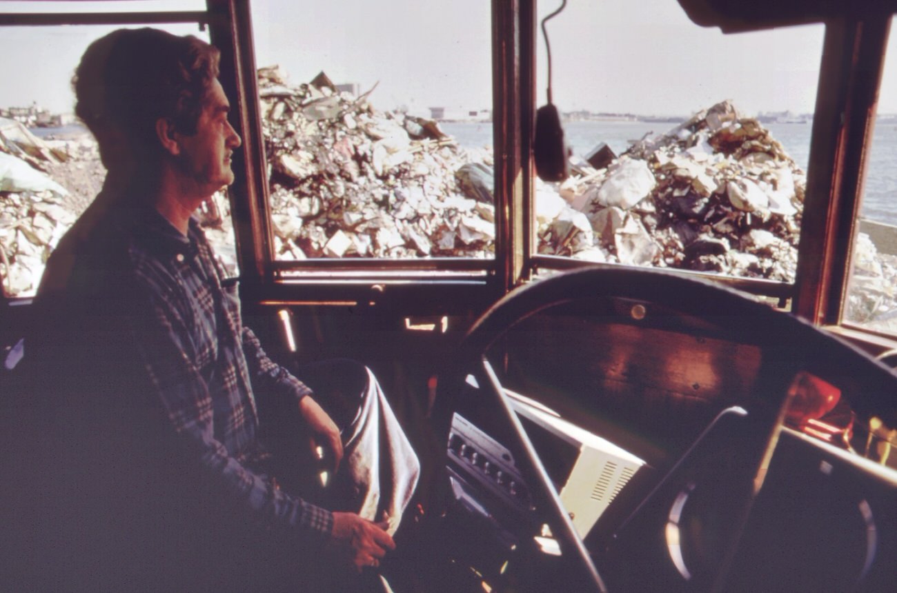 #74 Operator of steam-shovel used to unload garbage scows from manhattan sits in his cab at staten island landfill, 1970s