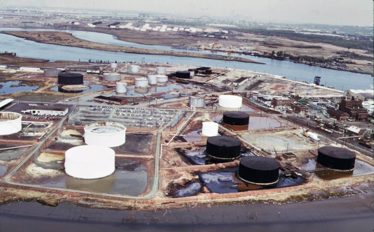 #84 American cyanimid and bp storage tanks on the new jersey side of arthur kill, with gulf oil tanks on staten island in background, 1970s