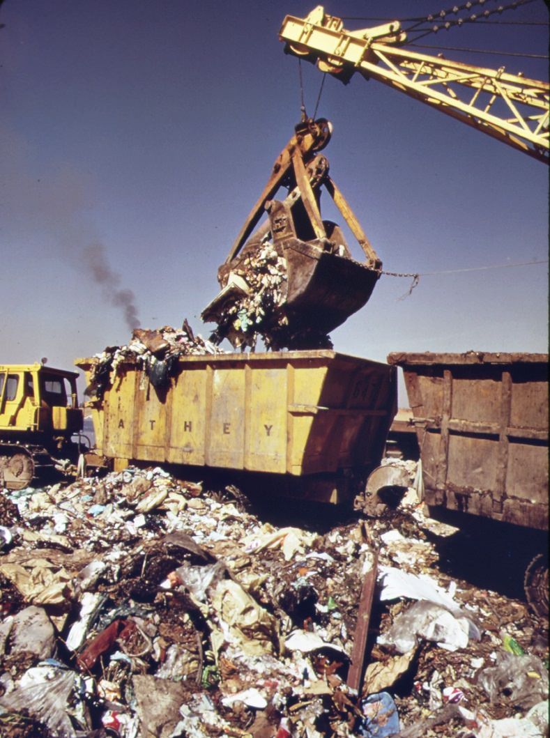 #93 At staten island landfill steam shovel loads carts with garbage brought by barge from manhattan. Carts will haul refuse to outer edges of dumping area, 1970s