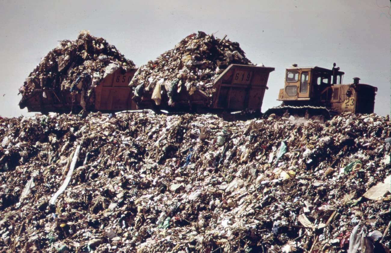#95 At staten island landfill. Carts heaped with garbage brought by barge from manhattan are about to dump their loads at outer edges of landfill area, 1970s