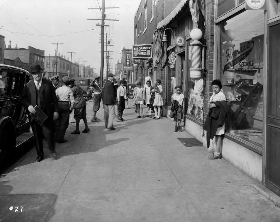 #84 Street view of Louis Lum Chop Suey at 1014 North Sarah and other businesses. Several people are on the busy sidewalk, 1930