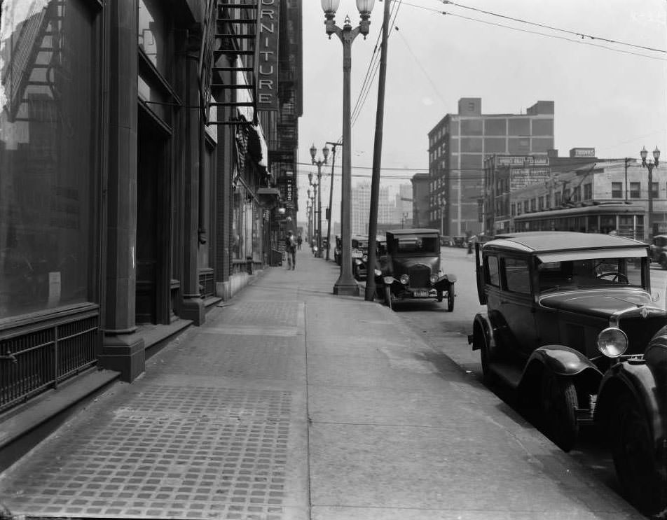 #149 View looking east down Olive from west of 18th Street. Several businesses including Quirk Luggage, Paris Hotel, Draper Drug Company, and Walker-Armstrong House Furnishing Company are visible, 1930