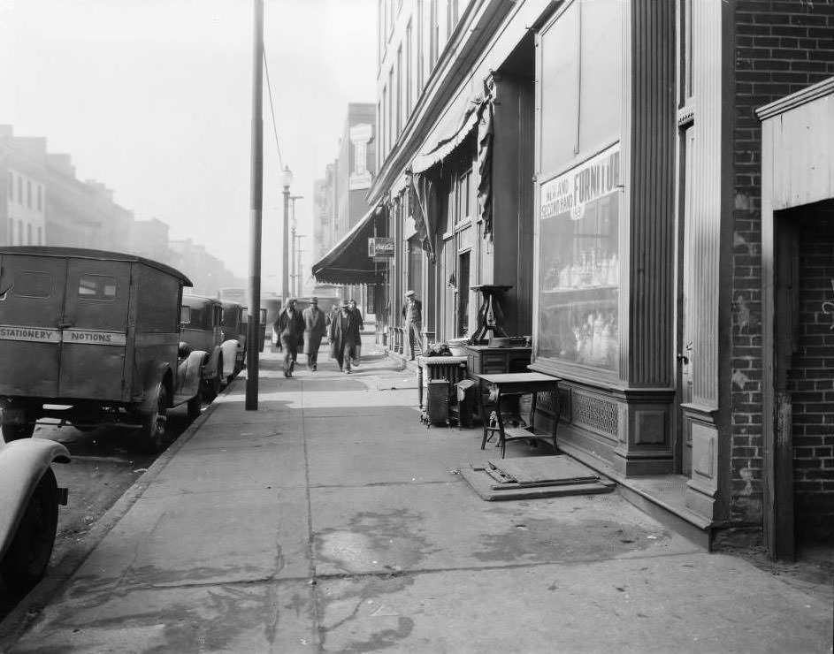 #77 Pedestrians and parked cars near Ludwig’s Drugs at 1939 Franklin Avenue with a used furniture store in the foreground, 1930