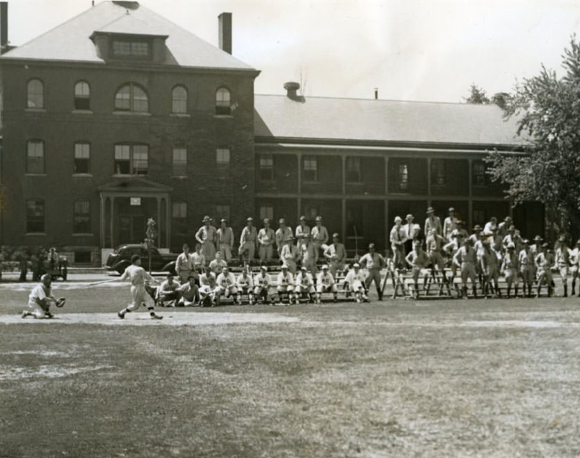 #94 Private dressed in baseball clothes plays a game while fellow soldiers watch in 1937.