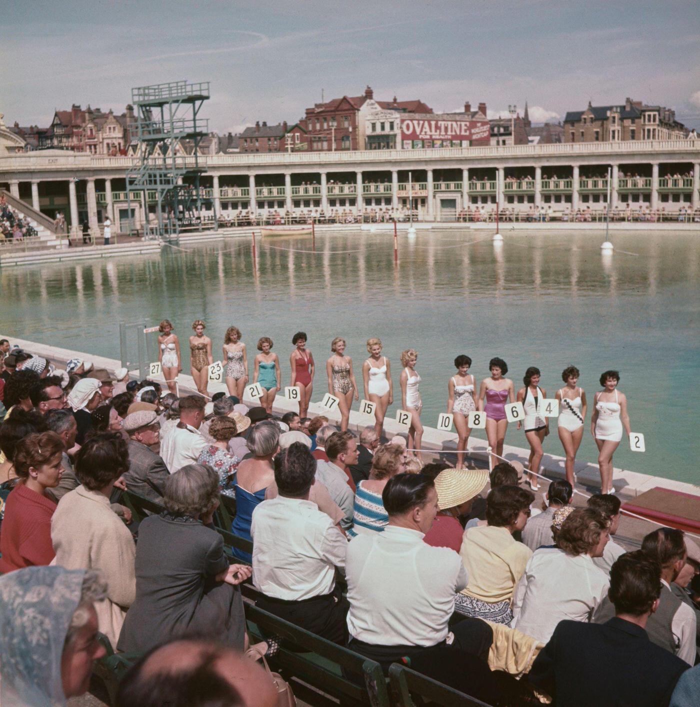 #67 A line up of women pose in bathing suits as they take part in a beauty contest at South Shore open air swimming pool, 1960