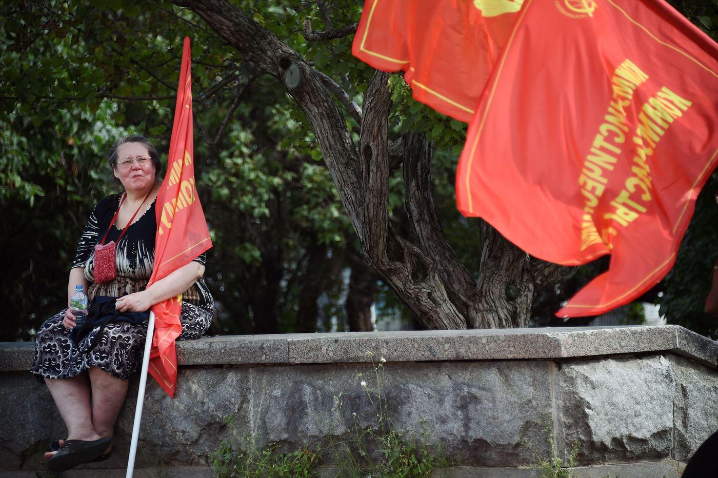 #7 Russian Communist supporter with red flag sits on a wall during rally in downtown Moscow marking the 25th anniversary of the August 1991 putsch.