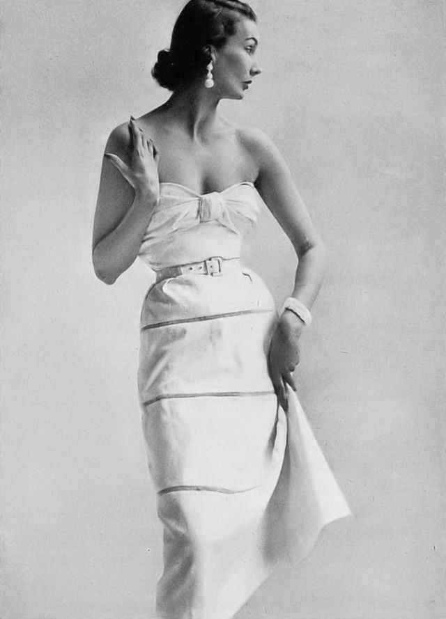 #19 Barbara Goalen in crisp white piqué dress, the skirt with rows of insertions, the tiny bolero hooks unto the bodice converting it to a day-dress by Atrima, 1951.