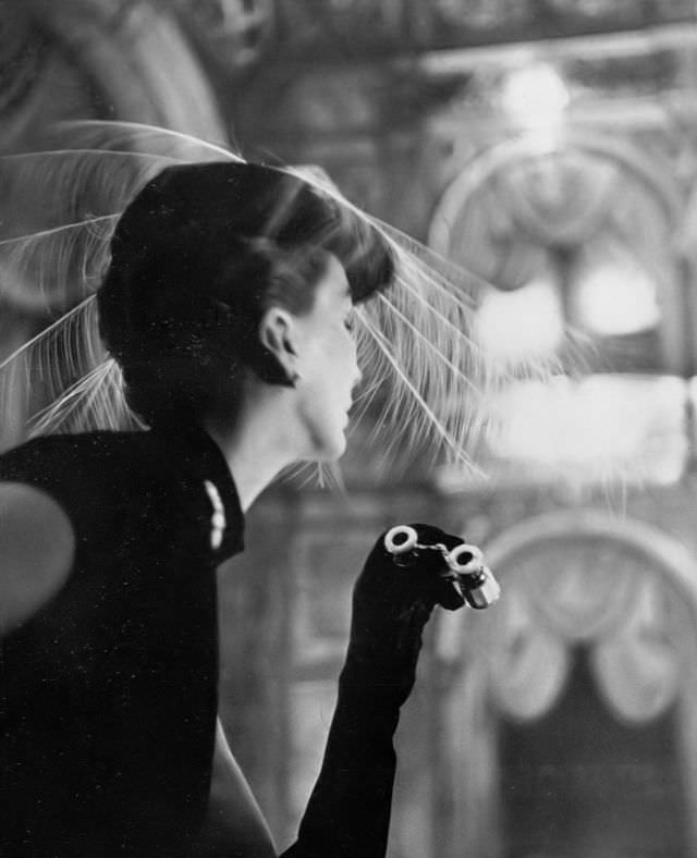 #24 Barbara Goalen is wearing a hat with a spray of white egret feathers by Rudolf, opera glasses by Asprey, 1951.
