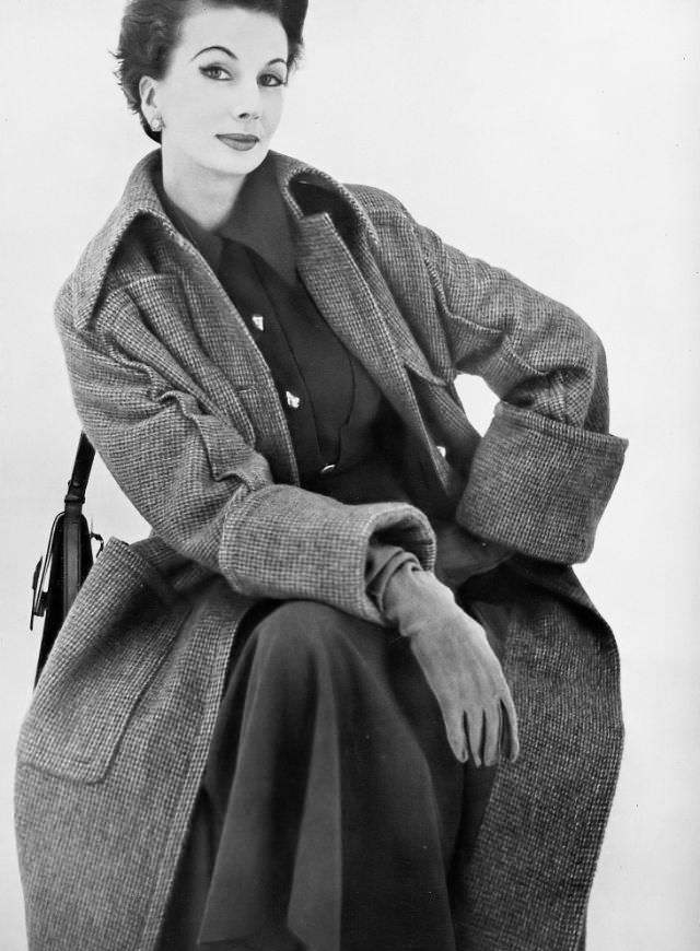 #28 Barbara Goalen in a greatcoat in a porridgy tweed, welted and cuffed, with gold buttons by Matita, handbag by Finnigan, 1952.
